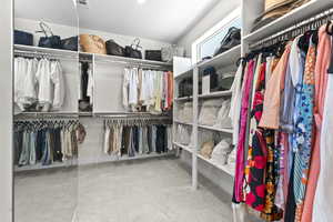 Primary Walk-in closet featuring light colored carpet