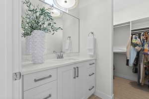 Bathroom with vanity, a walk in closet, and light tile patterned floors