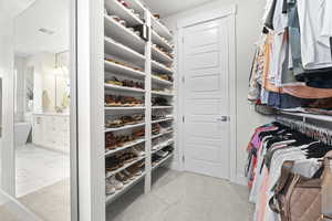 Spacious Primary closet with light colored carpet and built in shelving