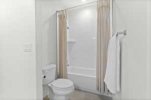Bathroom featuring shower / bath combination with curtain and light tile patterned floors