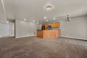 Kitchen with open floor plan, light colored carpet, recessed lighting, dark countertops, and a chandelier