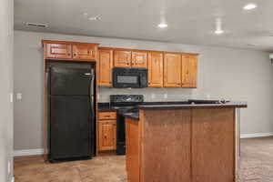 Kitchen with black appliances, recessed lighting, a center island, and dark stone counters