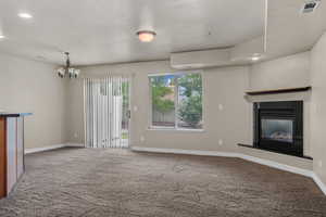 Unfurnished living room featuring recessed lighting, light carpet, a glass covered fireplace, and a chandelier
