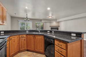 Kitchen featuring brown cabinets, black appliances, a chandelier, a fireplace, and recessed lighting
