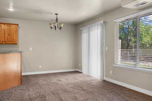 Unfurnished dining area featuring carpet floors and a chandelier