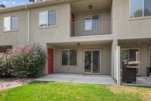 Rear view of house featuring stucco siding, a patio area, a balcony, and a yard