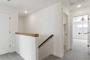 Corridor featuring light colored carpet, an upstairs landing, and recessed lighting