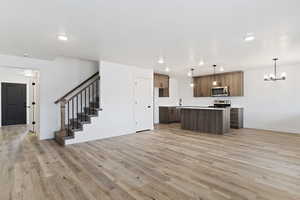 Kitchen featuring open floor plan, hanging light fixtures, light countertops, a center island, and light wood-style flooring
