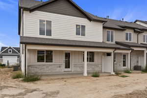 View of front of property featuring board and batten siding, stone siding, roof with shingles, and covered porch