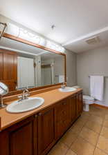 Bathroom with double vanity, light tile patterned flooring, a shower with shower curtain, and a textured ceiling