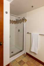 Bathroom featuring a shower stall, a textured ceiling, and light tile patterned flooring
