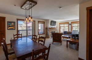 Dining room with a stone fireplace, carpet floors, and a chandelier