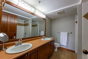 Full bath featuring a shower with curtain, double vanity, and light tile patterned floors