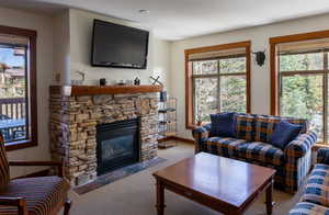 Carpeted living room featuring healthy amount of natural light and a stone fireplace