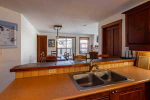 Kitchen featuring a peninsula, a breakfast bar area, decorative light fixtures, and dark countertops