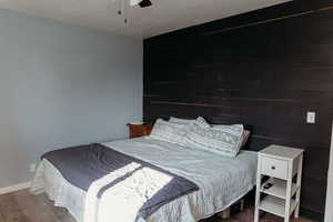 Master bedroom with laminate floors, wood feature wall and a ceiling fan