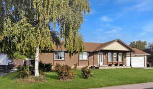 Single story home featuring a front lawn, an attached garage, driveway, and covered porch