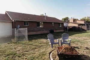 View of fenced yard featuring a gated dog area and fire pit