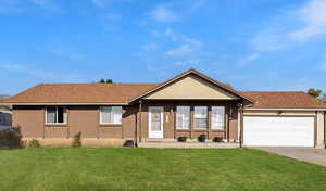 Ranch-style home featuring brick siding, a front lawn, an attached garage, driveway, and a shingled roof