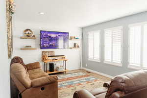 Living area with laminate floors, large windows  and recessed lighting