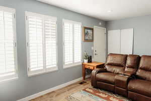 Living area with laminate floors, large windows  and recessed lighting