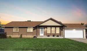 Ranch-style home with brick siding, a yard, attached garage and driveway
