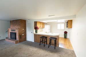 Kitchen featuring light countertops, a breakfast bar, light carpet, open floor plan, and a peninsula