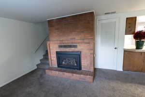 Unfurnished living room with stairs, carpet, and a fireplace