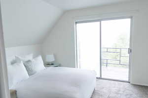 Bedroom with light carpet, access to exterior, and lofted ceiling