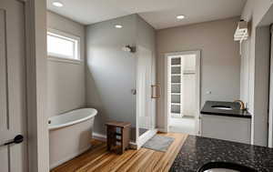 Full bathroom with a shower stall, light wood-type flooring, a freestanding bath, vanity, and recessed lighting