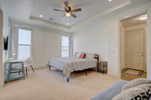 Bedroom featuring light colored carpet, a tray ceiling, recessed lighting, and ceiling fan