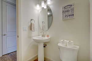 Half bathroom with toilet and wood finished floors
