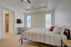 Bedroom featuring light colored carpet, recessed lighting, a tray ceiling, and a ceiling fan