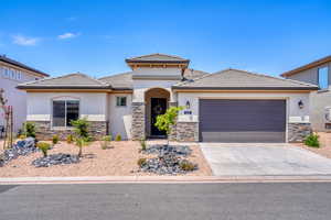 Prairie-style home featuring stone siding, stucco siding, driveway, and an attached garage