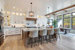 Kitchen featuring white cabinets, tasteful backsplash, decorative light fixtures, light stone counters, and recessed lighting