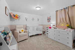Bedroom with light colored carpet and a nursery area