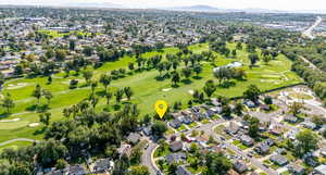 Aerial perspective of suburban area featuring a golf course and a water and mountain view