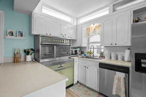 Kitchen featuring appliances with stainless steel finishes, white cabinetry, light countertops, a textured ceiling, and light wood-style floors