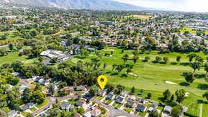 Aerial view of property and surrounding area with nearby suburban area, a golf course, and a mountain backdrop