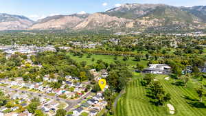 Aerial view of residential area featuring a mountainous background and a golf course