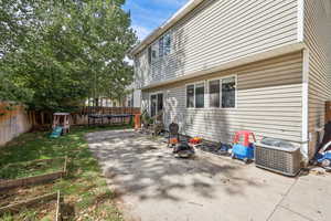 Fenced backyard with a trampoline, a patio area, a vegetable garden, and a playground