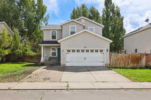 Traditional home featuring covered porch, driveway, stucco siding, and a garage