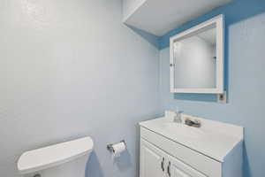 Half bathroom featuring a textured wall and vanity