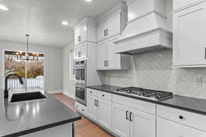 Kitchen featuring light wood-style floors, pendant lighting, white cabinetry, premium range hood, and recessed lighting
