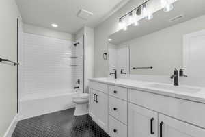 Full bathroom featuring tub / shower combination, double vanity, dark tile patterned floors, and recessed lighting