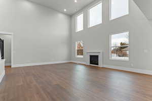 Unfurnished living room with a glass covered fireplace, a high ceiling, light wood-style floors, and recessed lighting