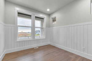Spare room featuring a wainscoted wall, hardwood / wood-style flooring, and recessed lighting
