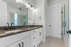 Bathroom with a stall shower, double vanity, and light tile patterned floors