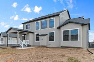 Back of house featuring stucco siding, a porch, and roof with shingles