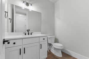 Half bath featuring dark wood-type flooring and vanity